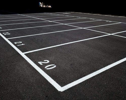 Background of the floor of an empty car park with white painted lines on the ground