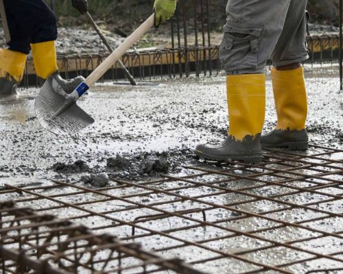 two bricklayers who level the freshly poured concrete to lay the foundations of a building